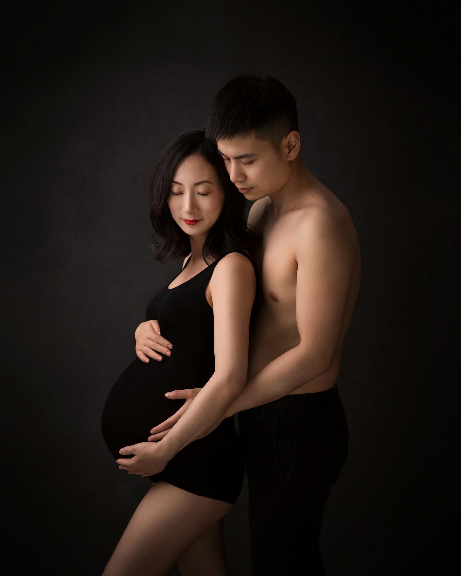 Pregnant lady is cuddled by her husband during maternity photoshoot