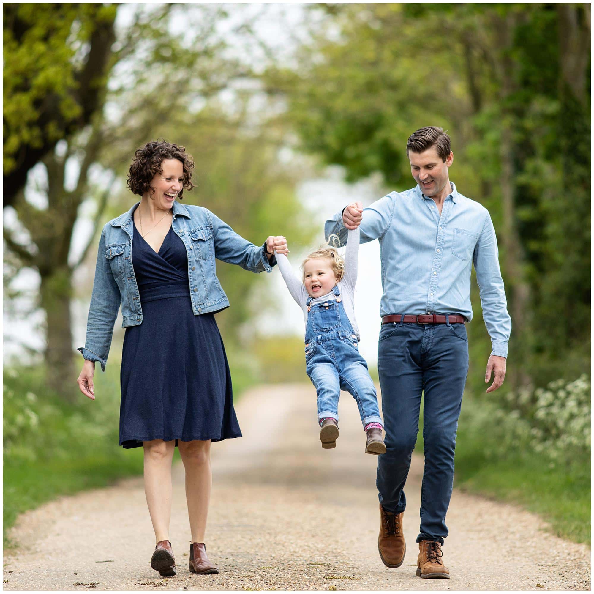 Mother and Father walk with their little girl on a country lane in Suffolk