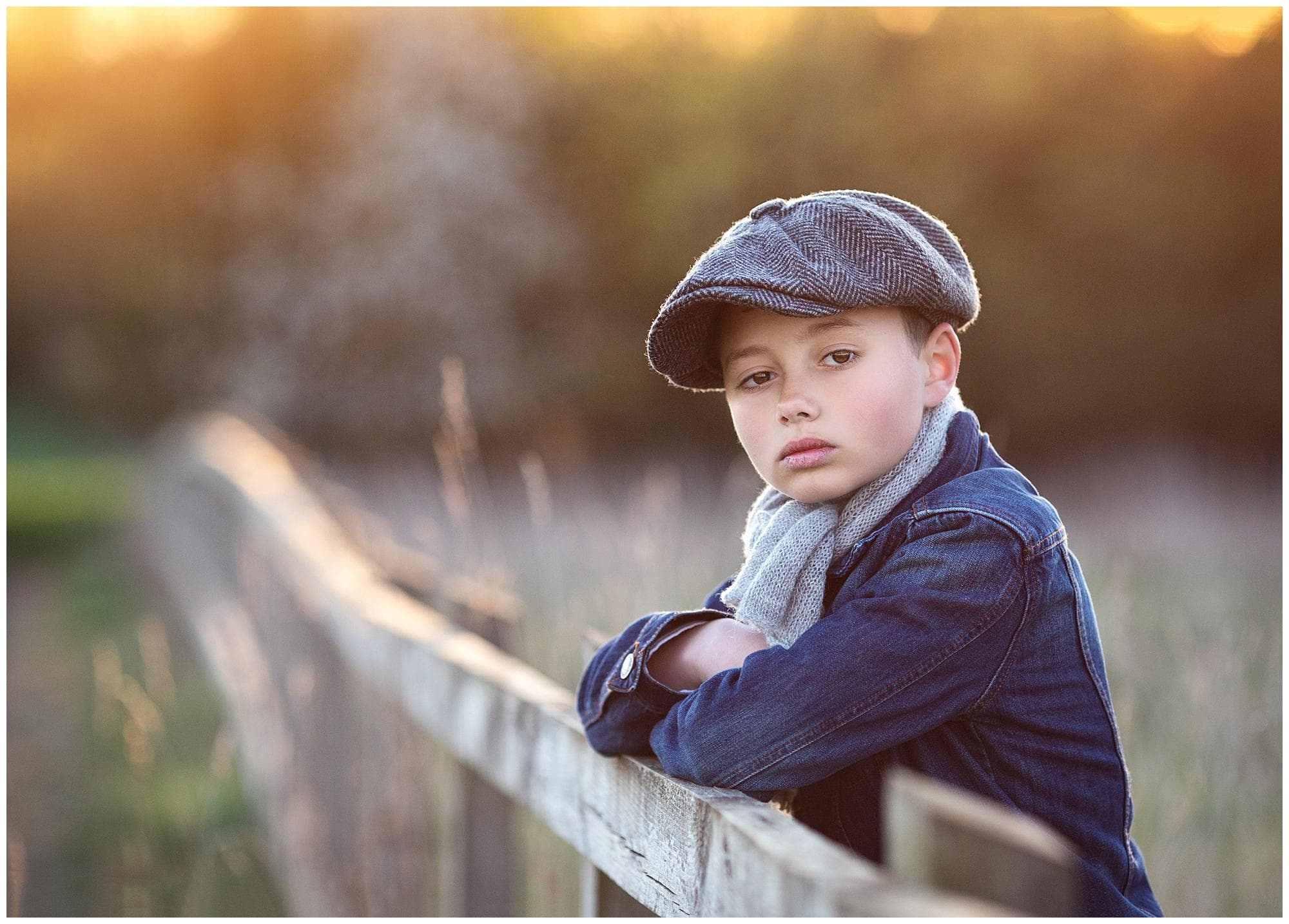 Boy in Denim and flat cap leans on a fence during golden hour in Stoke By Clare, Suffolk