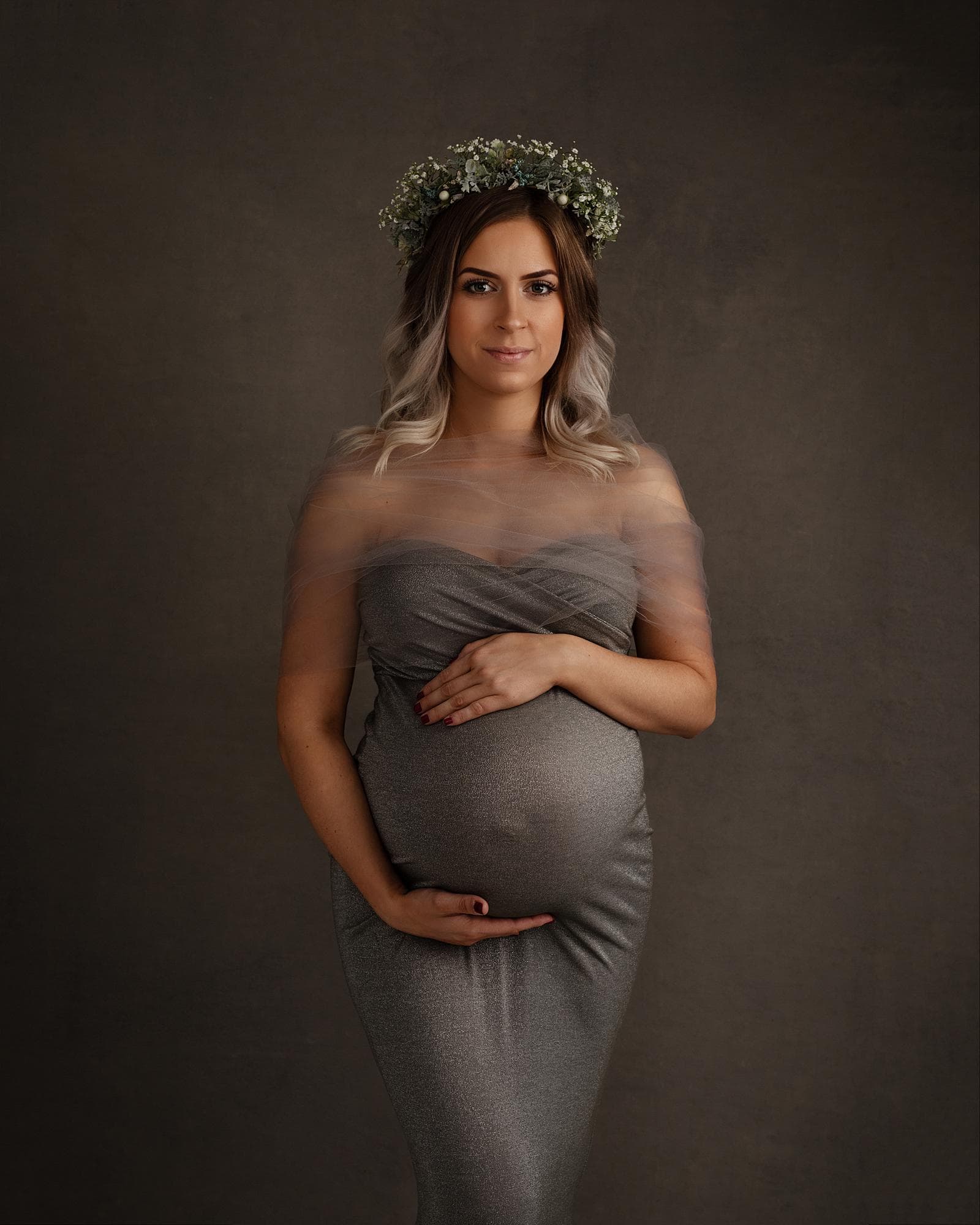 Pregnant woman posing in a grey dress for a maternity photoshoot in Alison McKenny's Suffolk studio