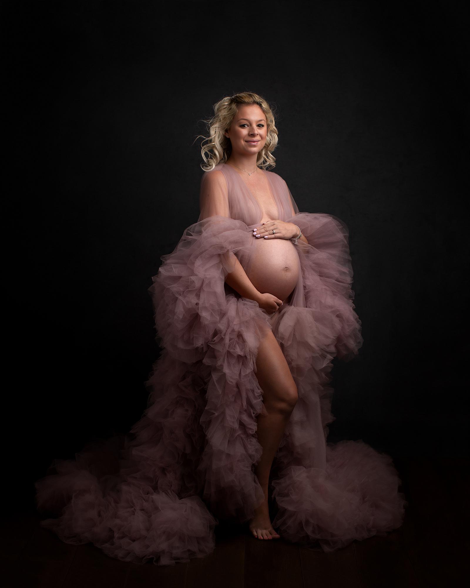 Pregnant woman posing in a sheer pink gown for a maternity photoshoot in Alison McKenny's Suffolk studio
