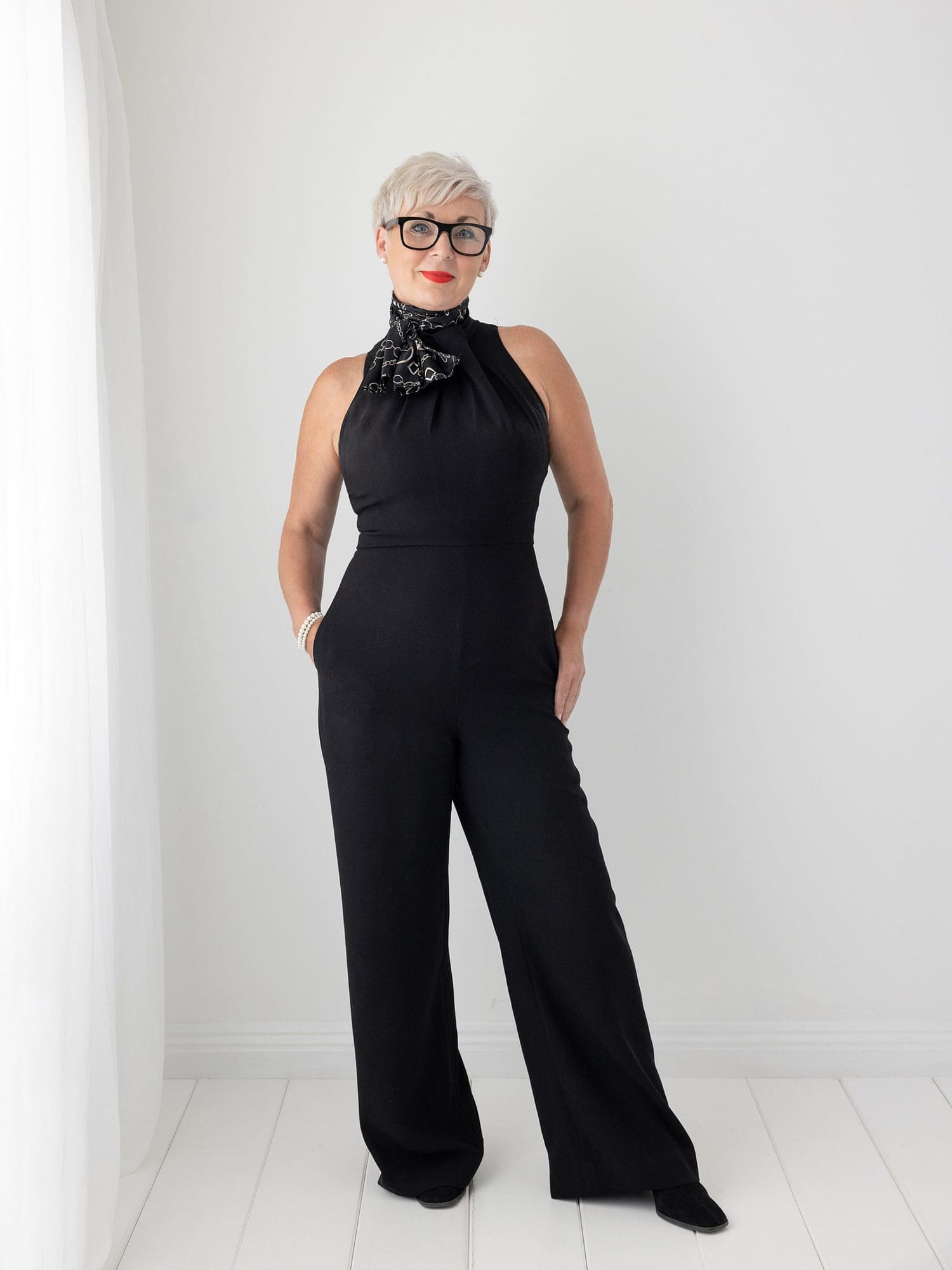 Beautiful woman with short grey hair posing for her Beauty Shoot against a white backdrop wearing a black jumpsuit in Suffolk Studio