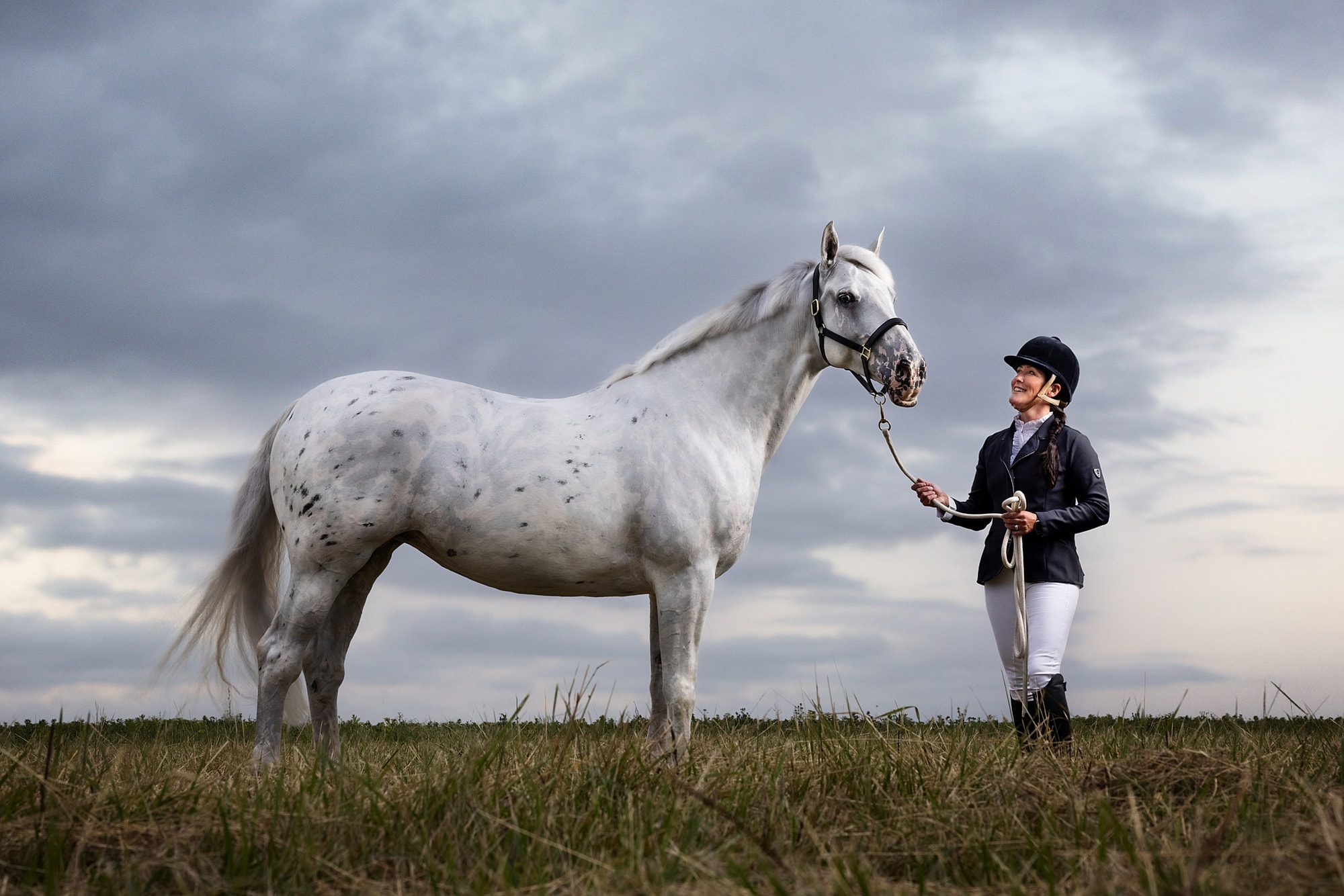 Fine Art Photograph of a grey horse and rider in a Suffolk field with a dramatic cloudy sky