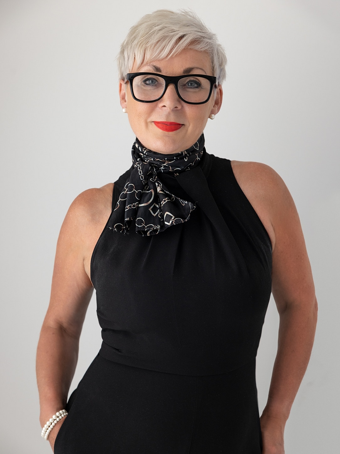 Personal Branding Portrait of lady with short blond hair and black jumpsuit on black background
