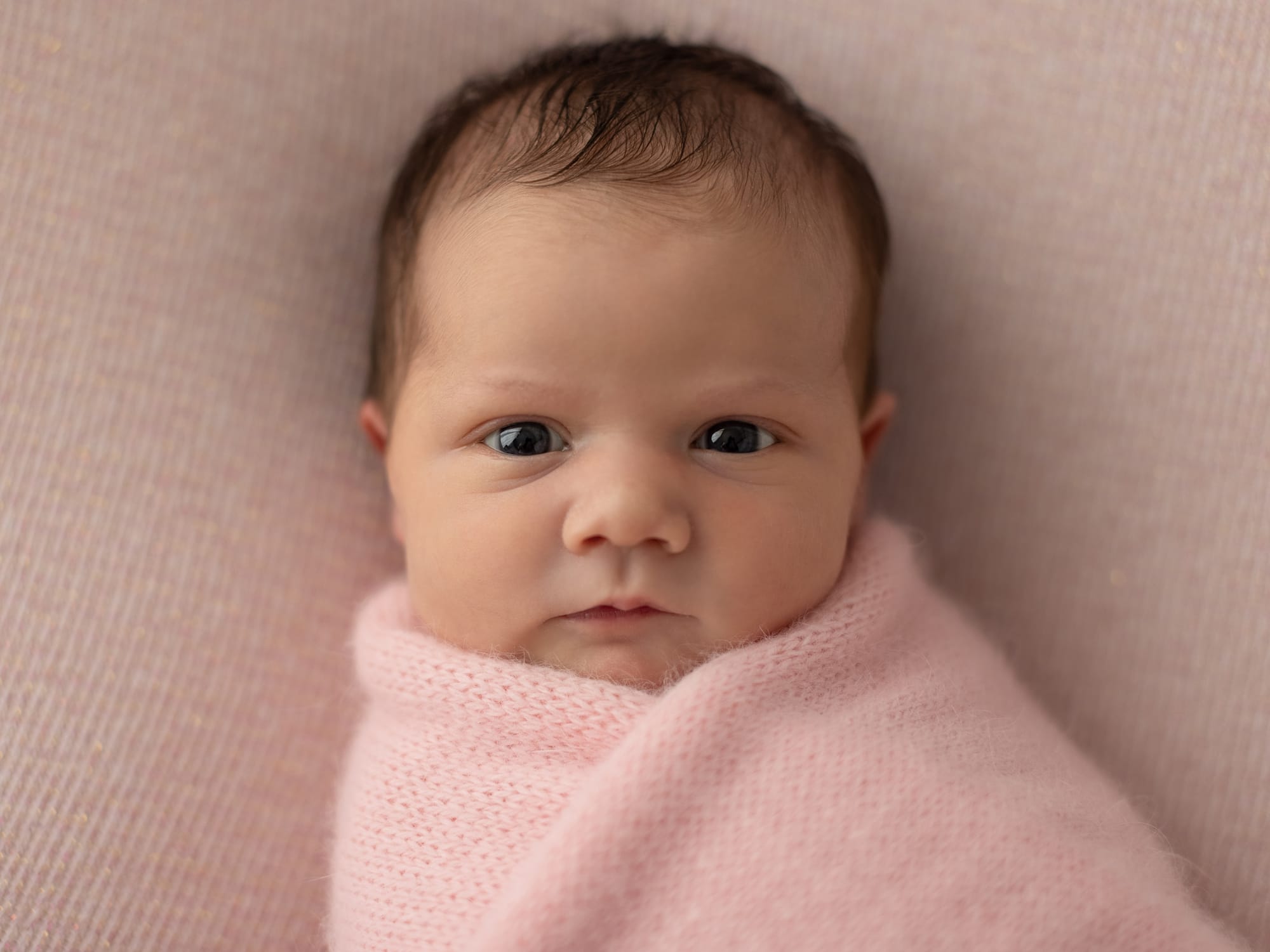 Headshot of Newborn Baby Girl on a pink blanket in a pink wrap