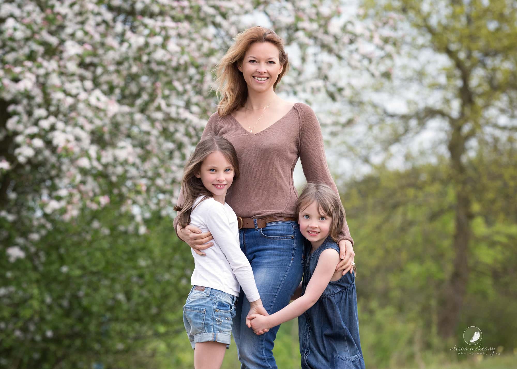A mother and her daughters posing during a Spring Mini Session in Suffolk countryside