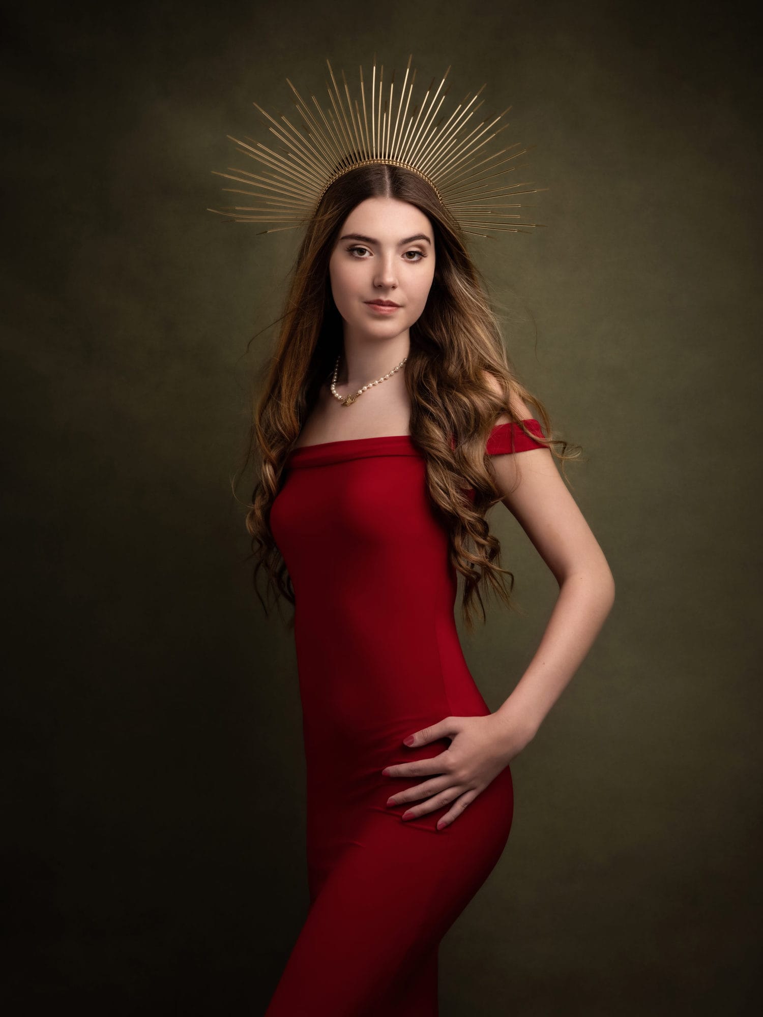 Beautiful teenage girl in a red dress and gold crown poses during her Beauty Shoot at Suffolk studio