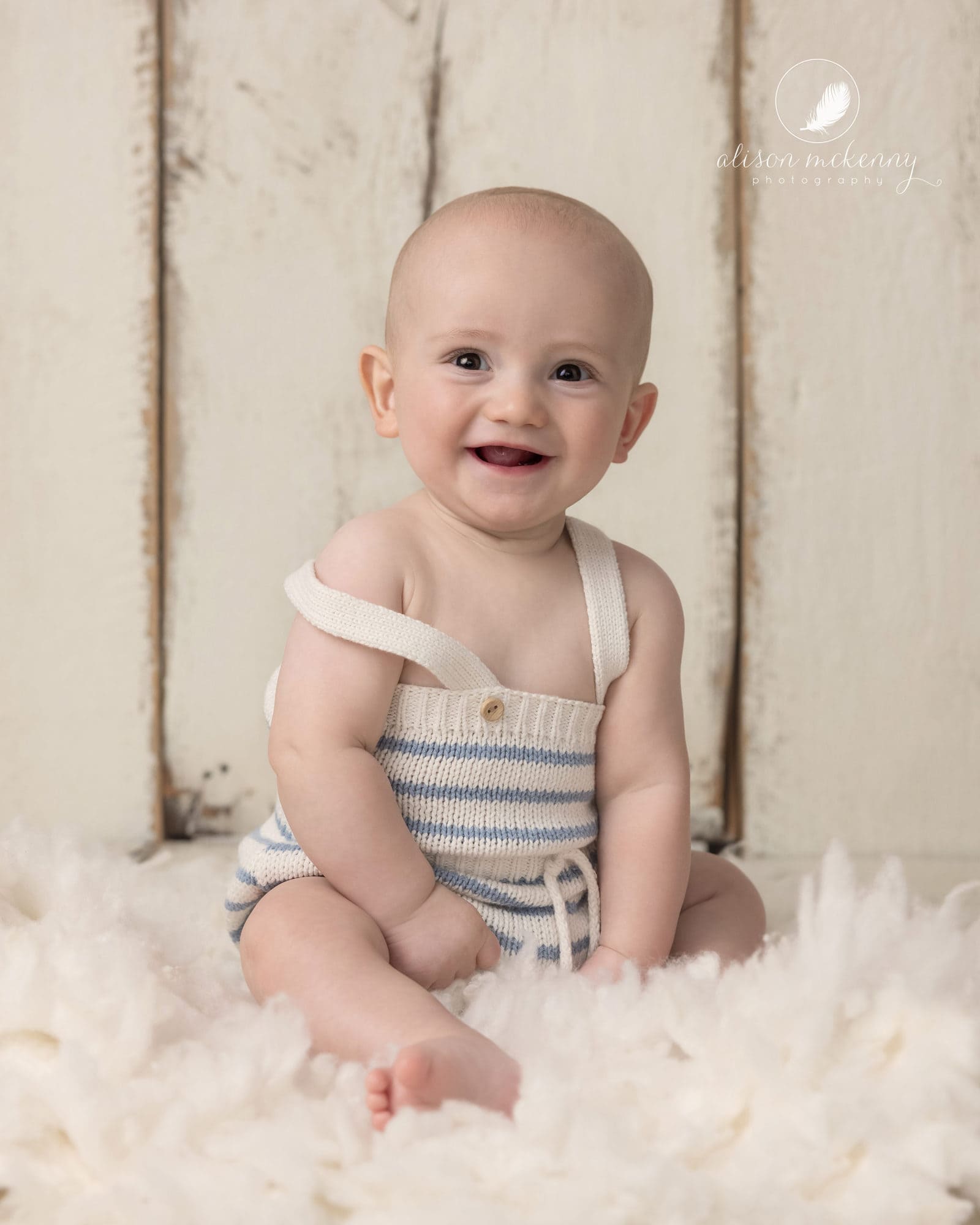 Smiling baby on cream background and fur rug
