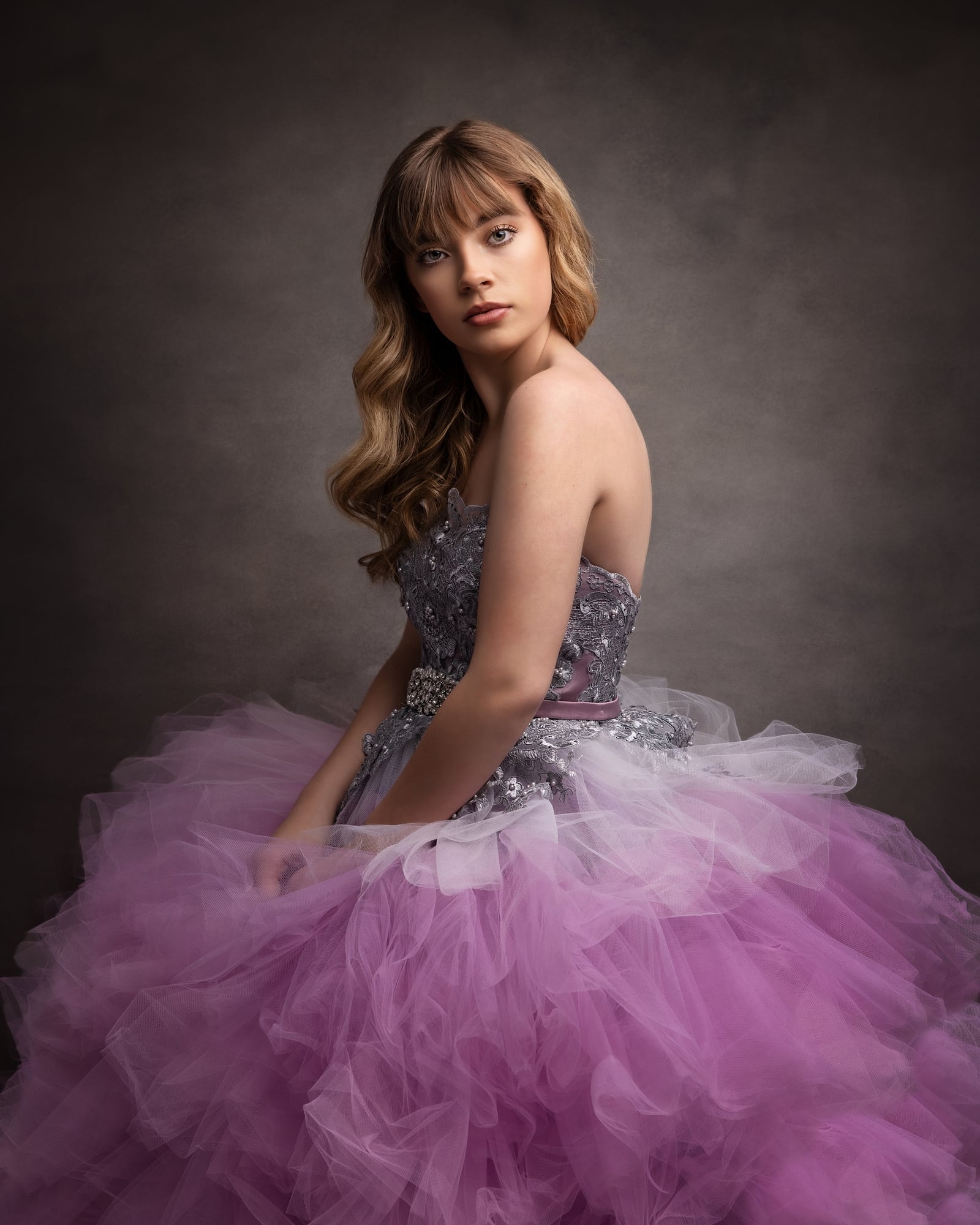 Teenage girl in a purple tulle dress looks at the camera
