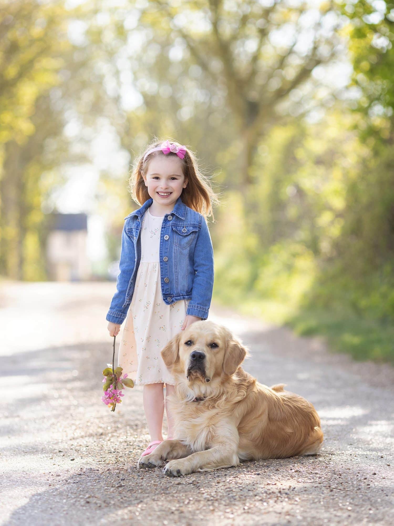 Little girl smiles with her Golden Retriever Dog during a Spring Mini Family Photoshoot in Suffolk