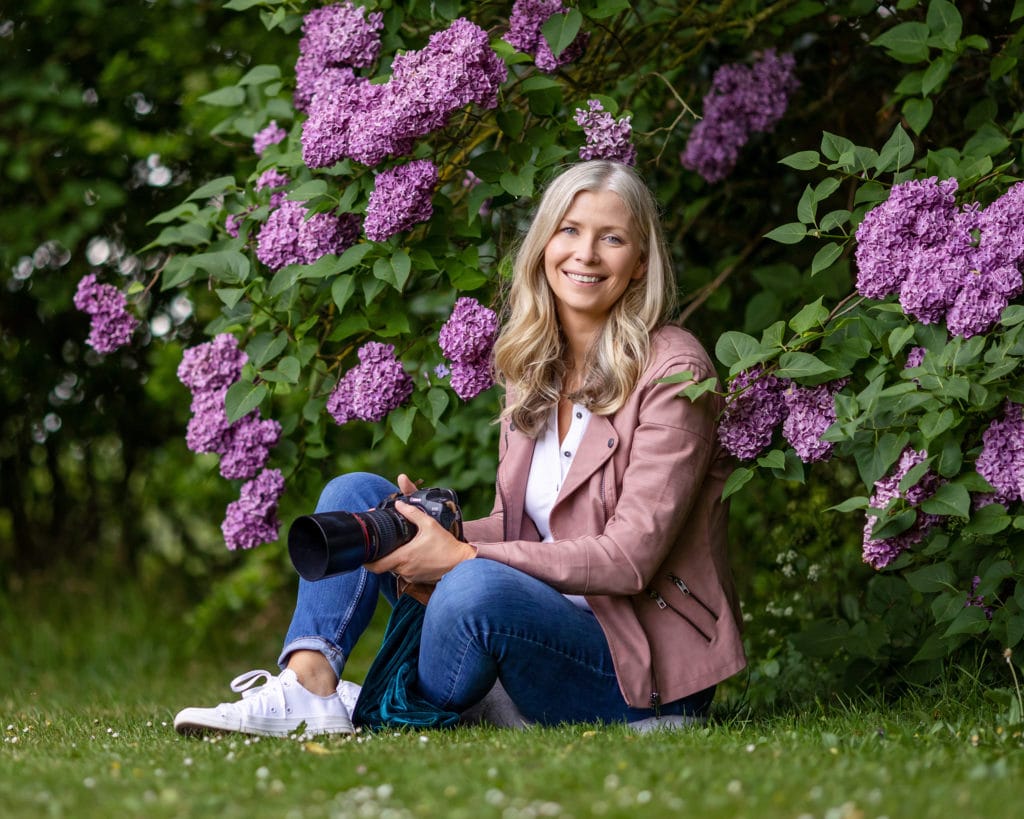 Portrait Photographer Alison McKenny sits under a lilac bush for a personal branding photo