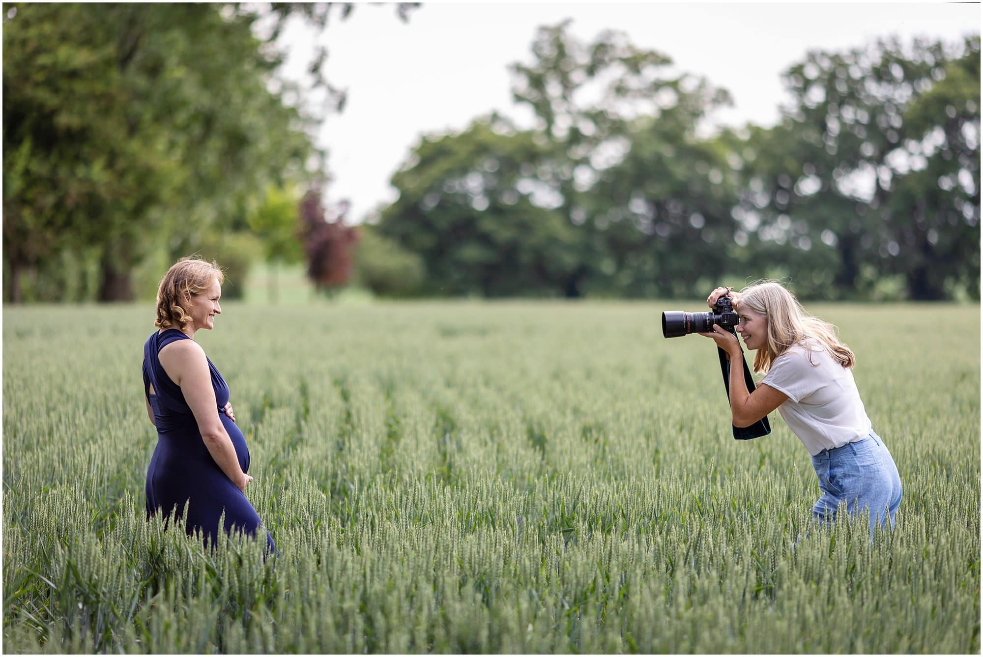 Behind the scenes photo of Alison McKenny photographing a maternity shoot in a wheat field
