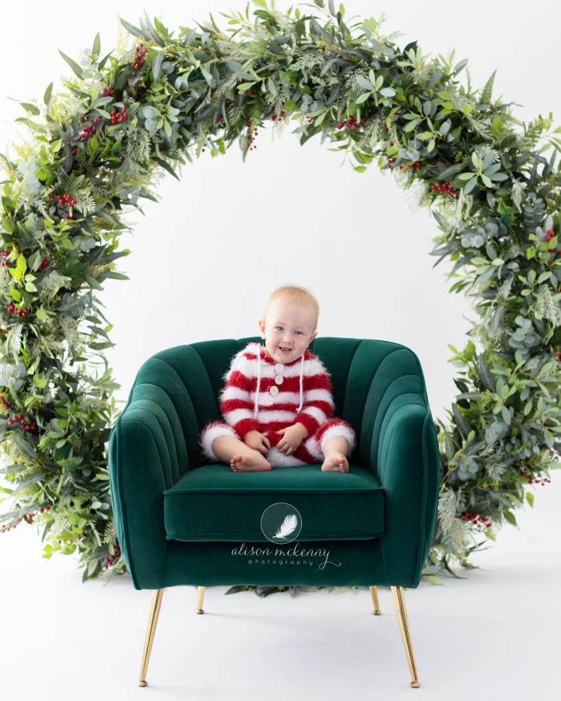 Baby on a green velvet chair during Christmas Mini Session in Suffolk