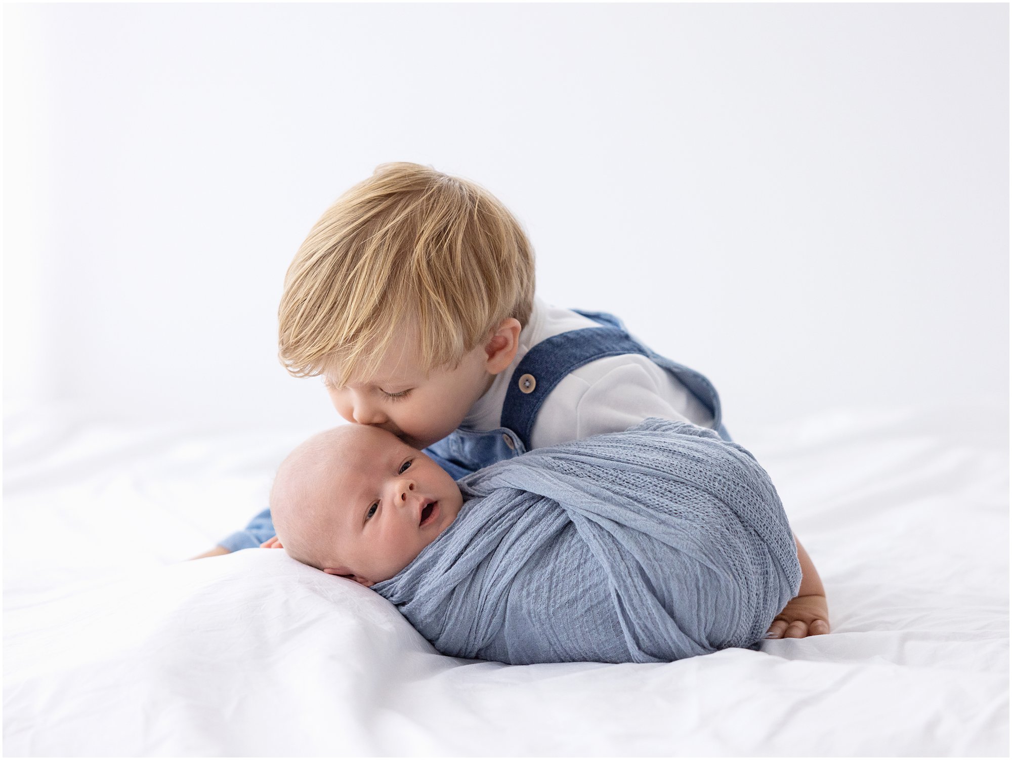 Toddler kisses his newborn Baby Brother during a Newborn Photoshoot with Alison McKenny Photography