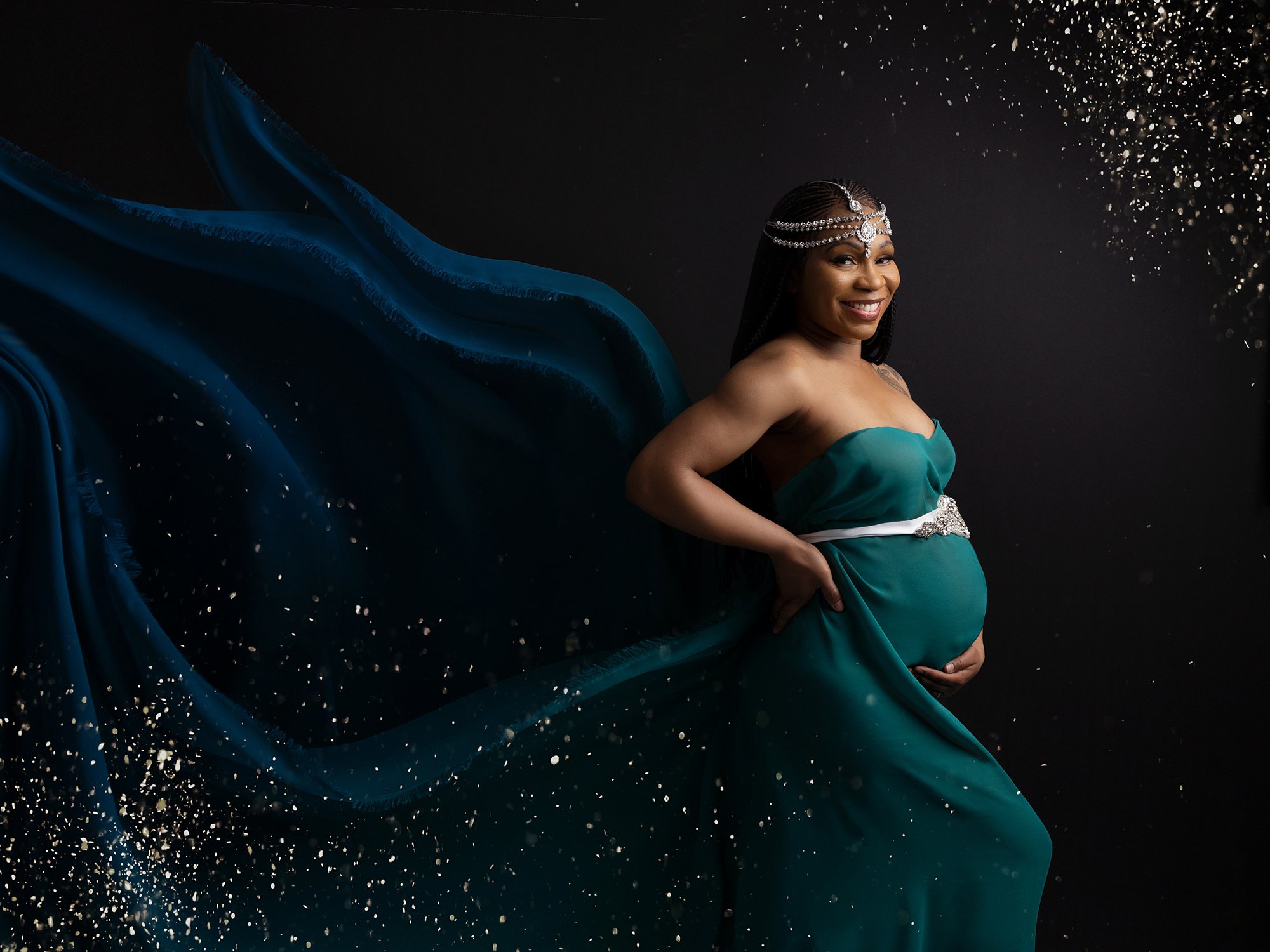 Pregnant lady in green and blue dress and crown poses during maternity photoshoot with Suffolk Photographer Alison McKenny