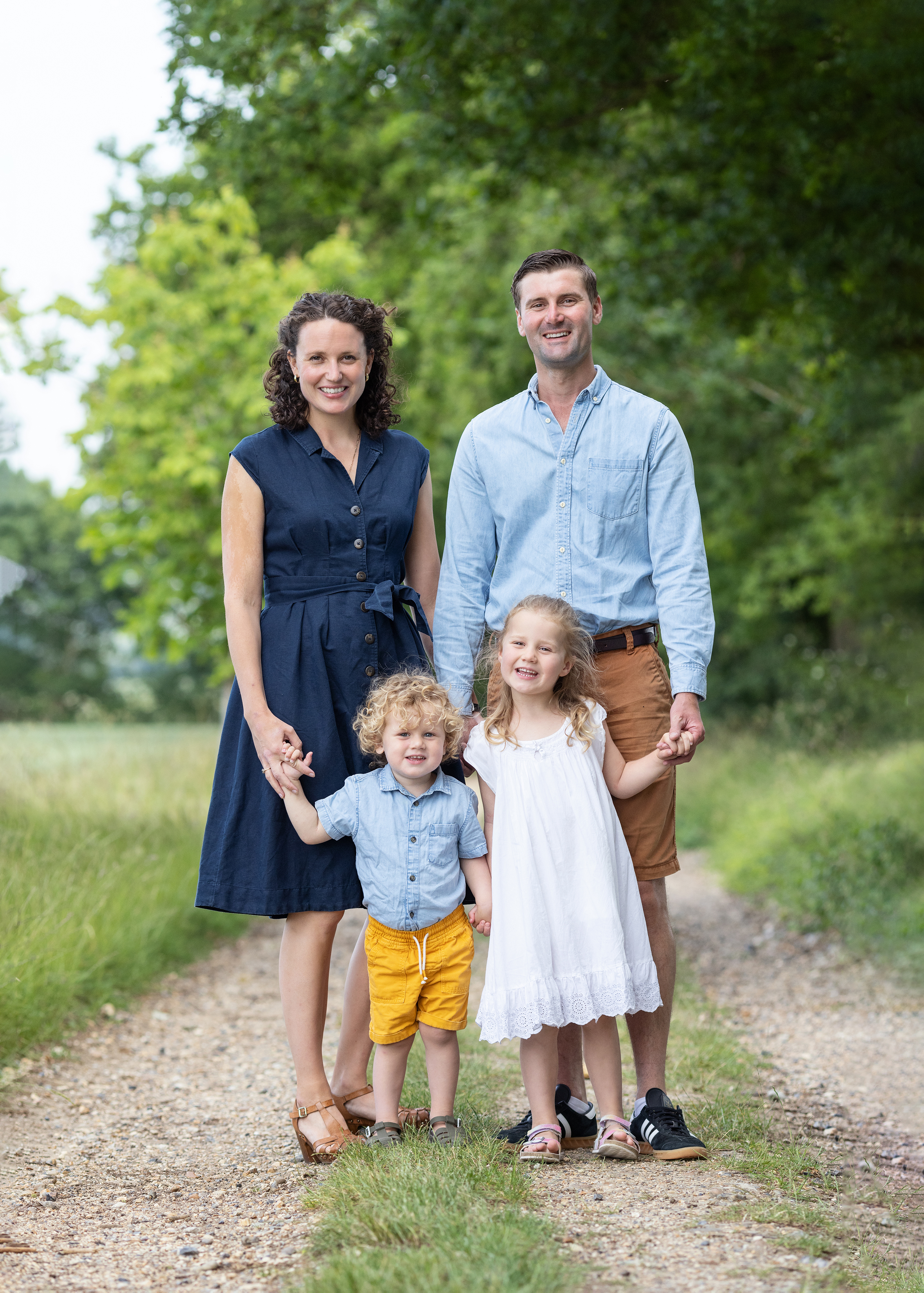 Family of 4 smile and hold hands during family photoshoot with Alison Mckenny