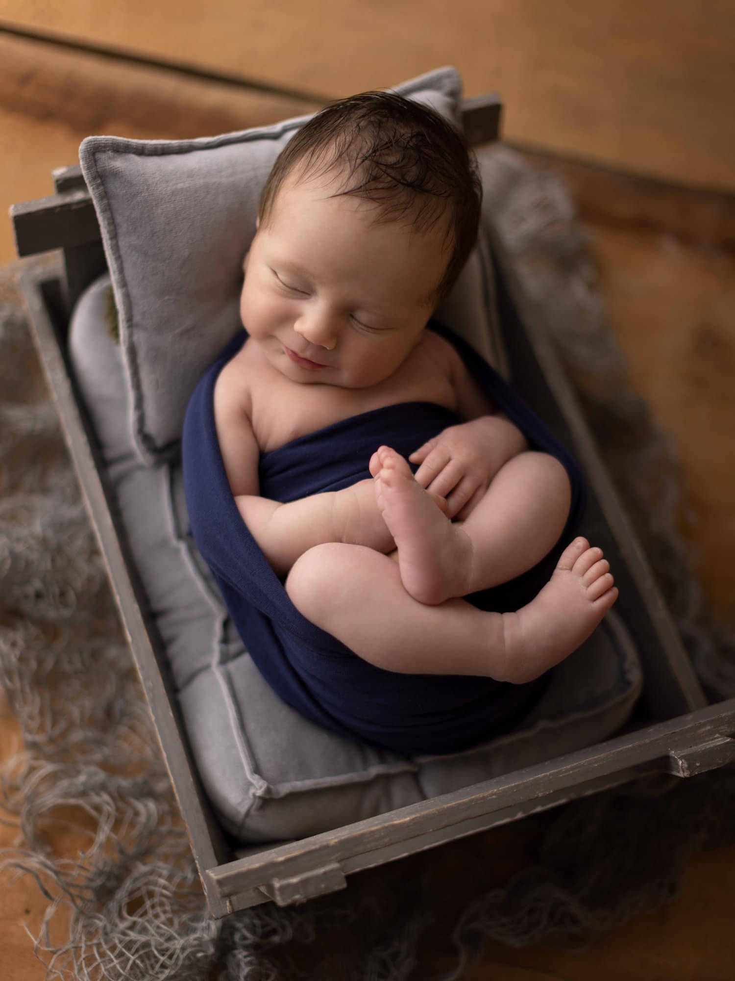 Newborn baby boy on grey bed during photoshoot with Alison McKenny Photography