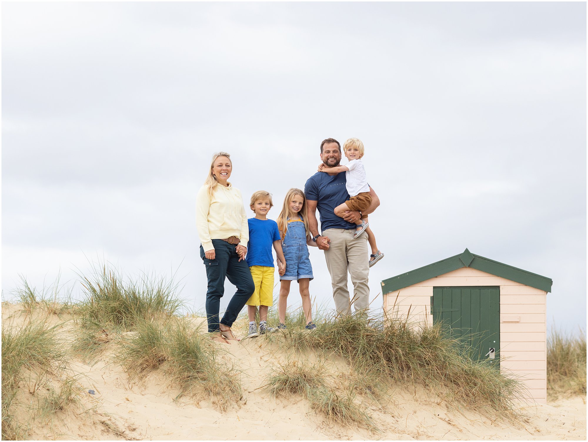 Family of 5 stand on the sand dunes on Southwold beach in Suffolk during family photoshoot with Alison McKenny Photography