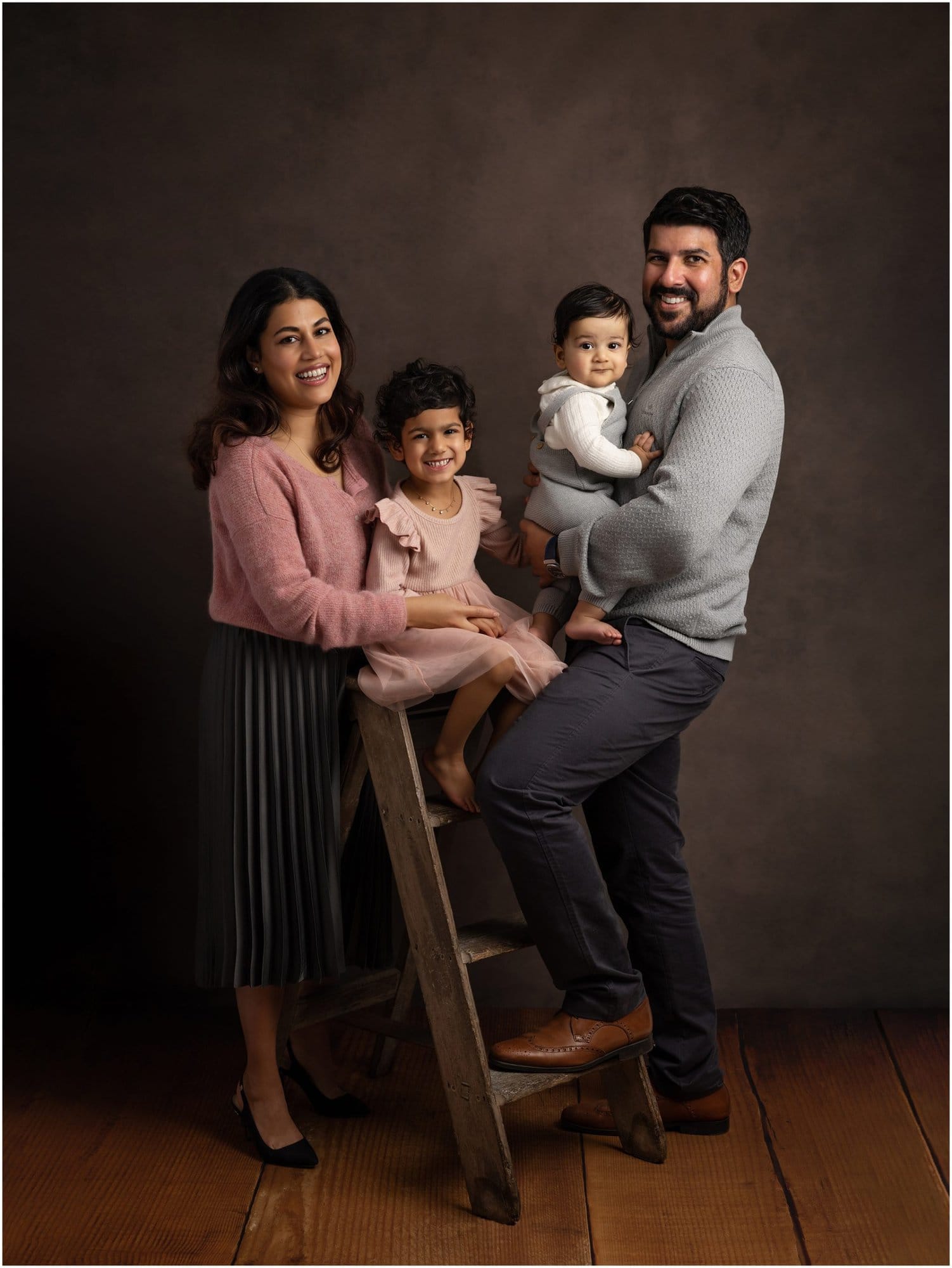 Beautiful family with young children smile during family portrait on brown background