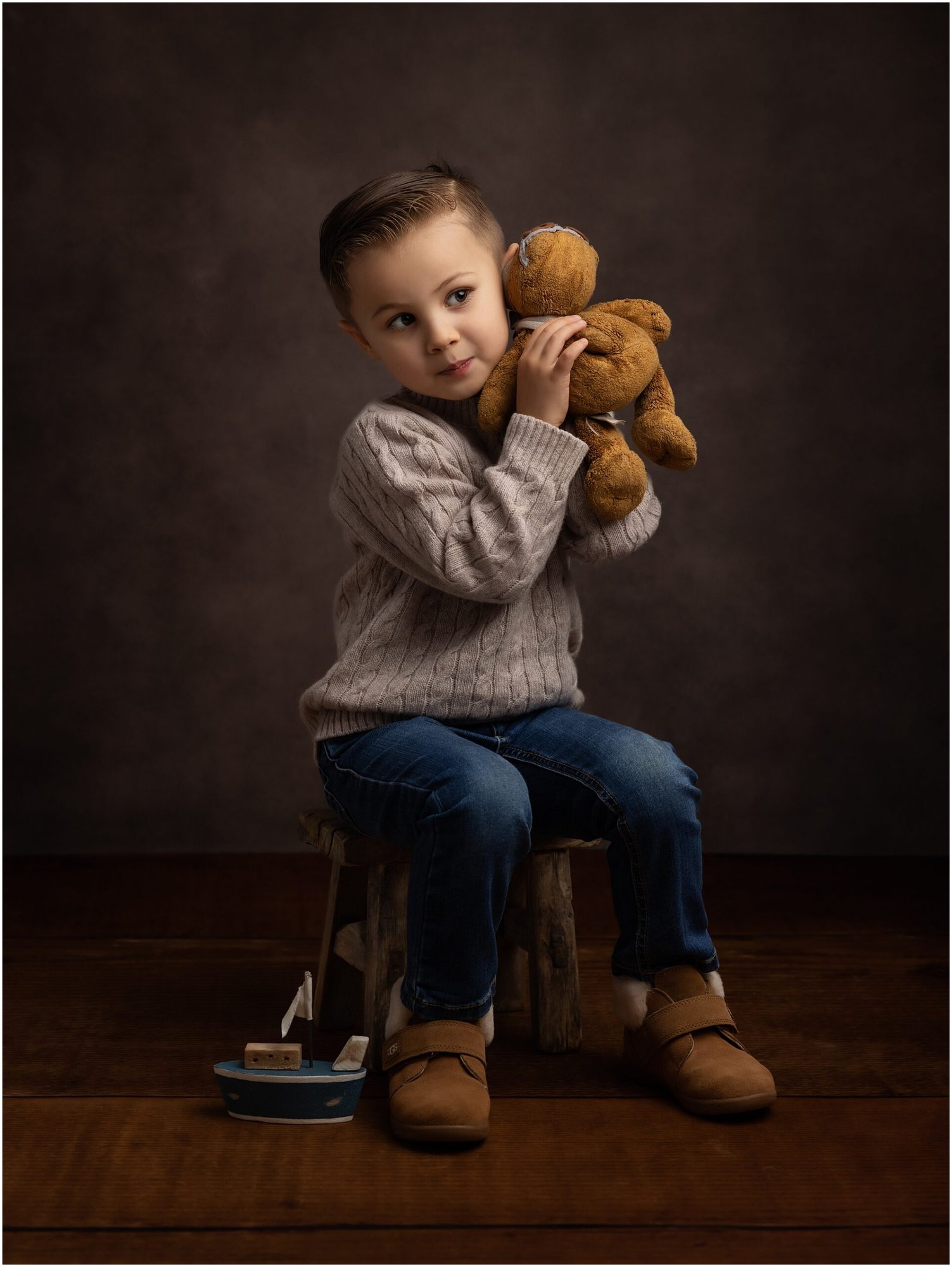 Little boy listens to his bears secrets during fine art shoot in suffolk studio