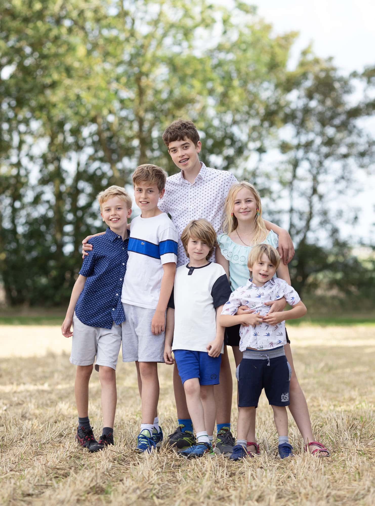 Cousins hug each other during an Extended family photoshoot on suffolk farm with Alison McKenny