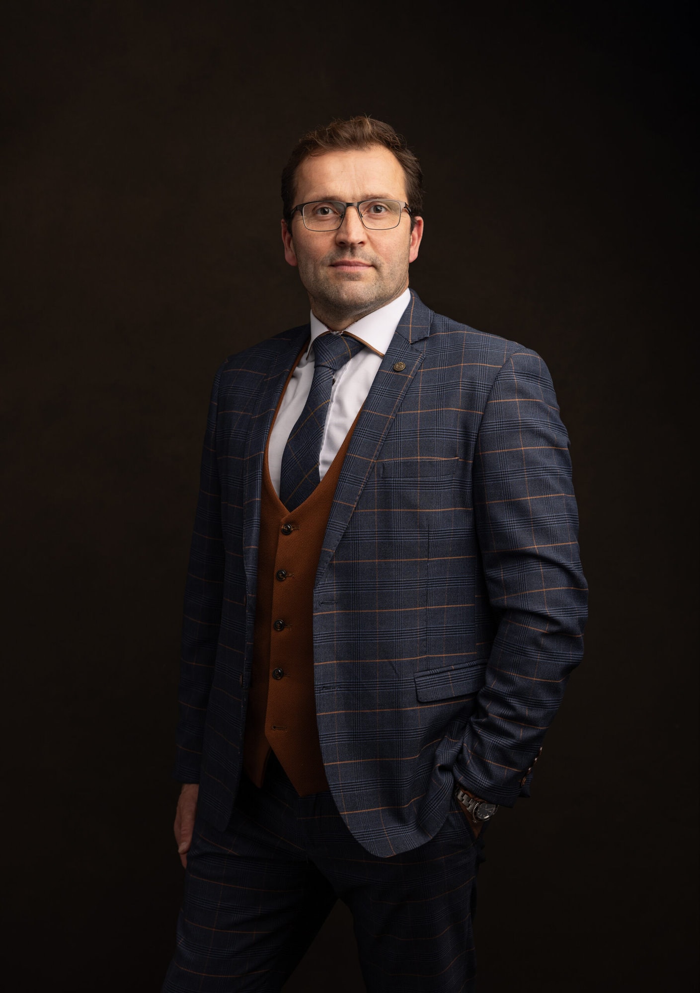 Handsome man with navy and brown checked suit poses for Headshot with Alison McKenny Photography