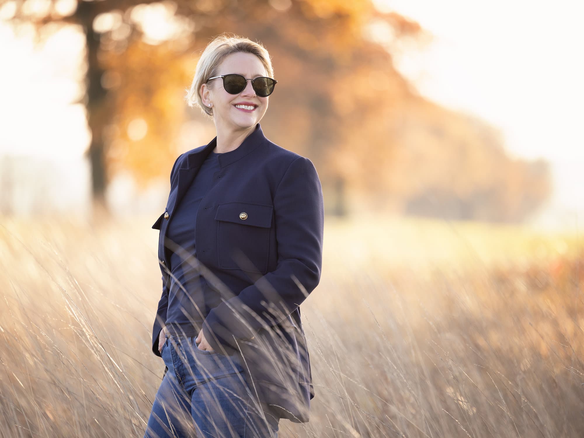 Personal branding portrait of a Nutritionalist and life coach smiling while looking over her shoulder while walking in a field of long grass
