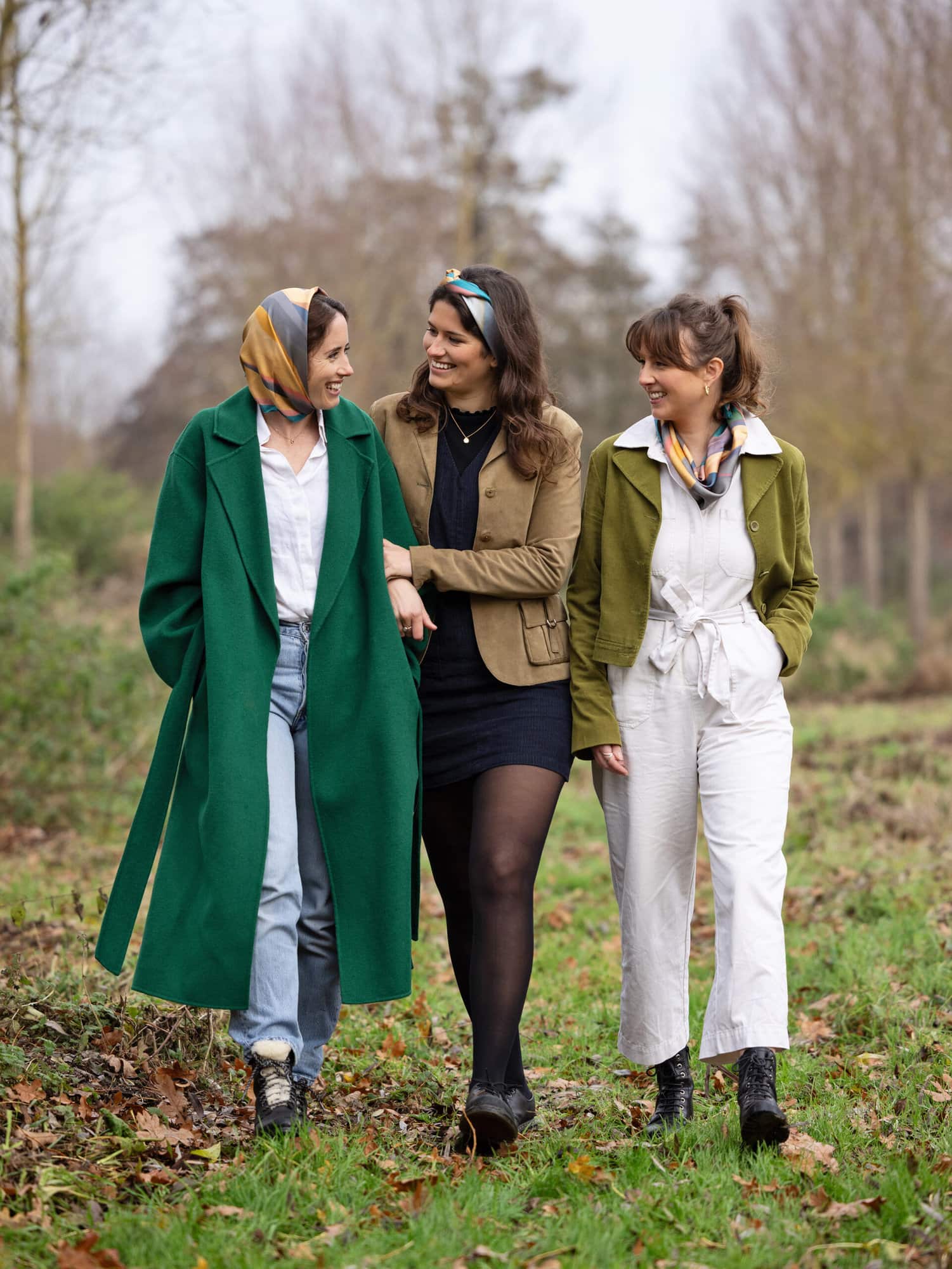 Three women walk arm in arm in the countryside wearing Mai Norman Headscarves. Photographed by Alison McKenny Photography