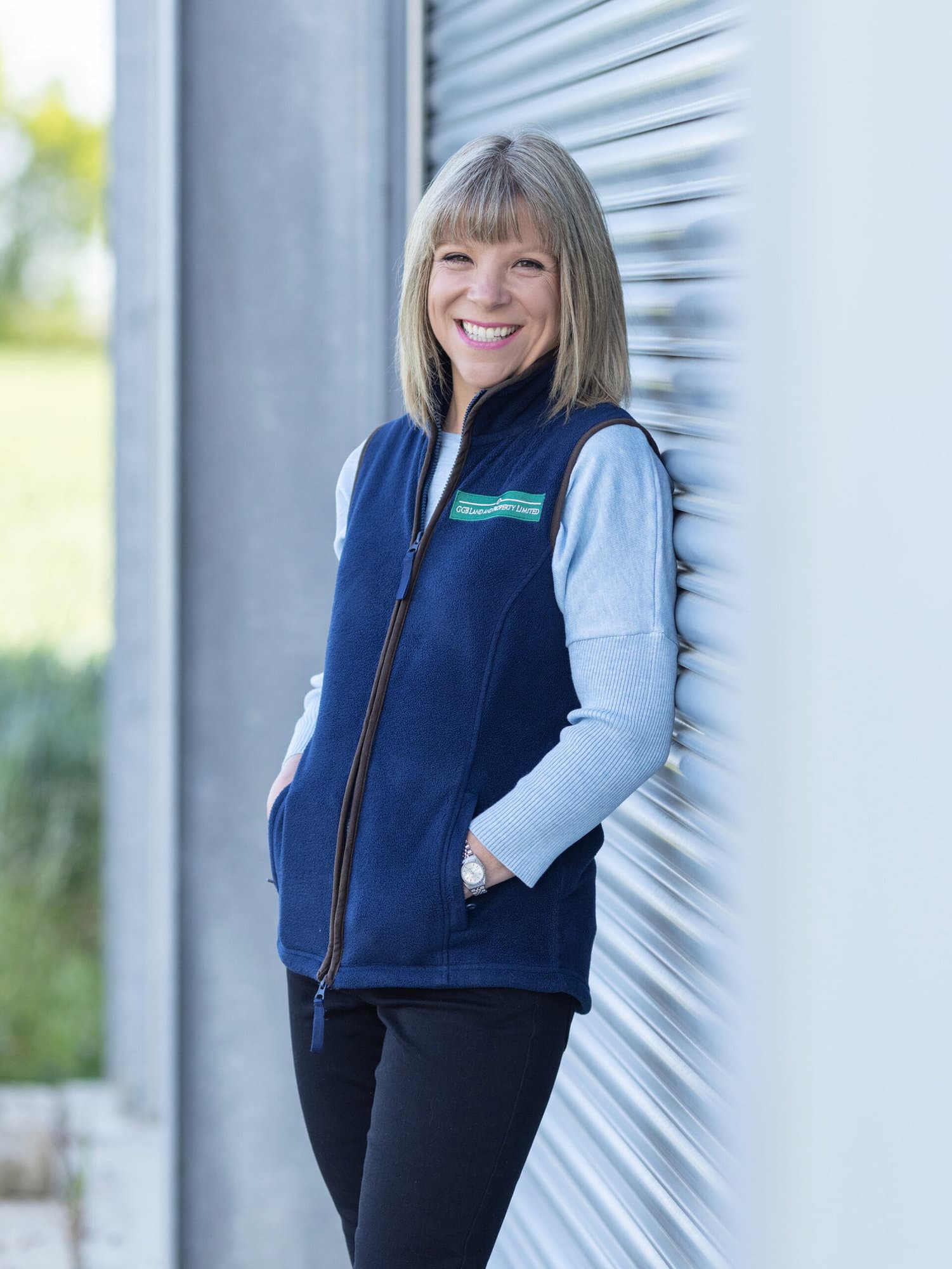 Land agent branding portrait of a woman leaning against a grain store barn door.