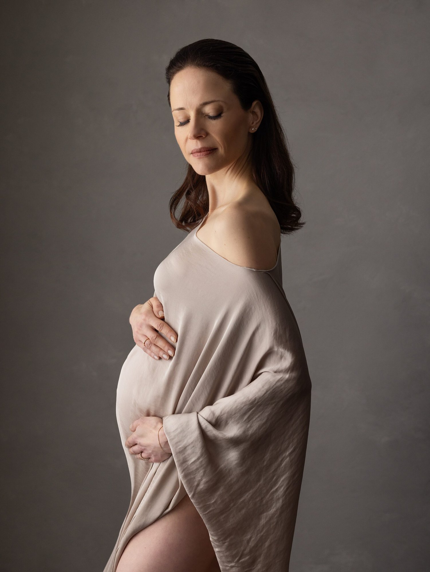 Maternity photo of a dark haired woman wearing a mocha silk dress during Maternity shoot with Alison McKenny Photography